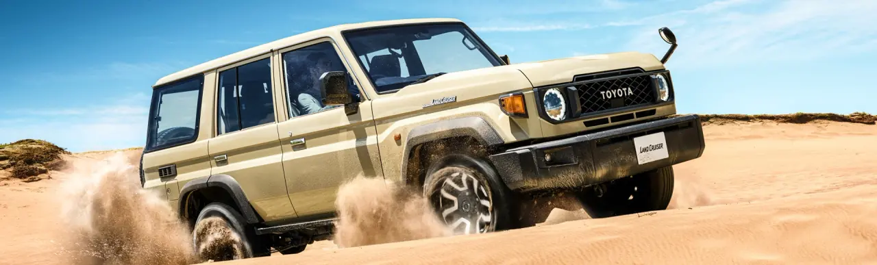 Toyota Land Cruiser driving through desert sand
