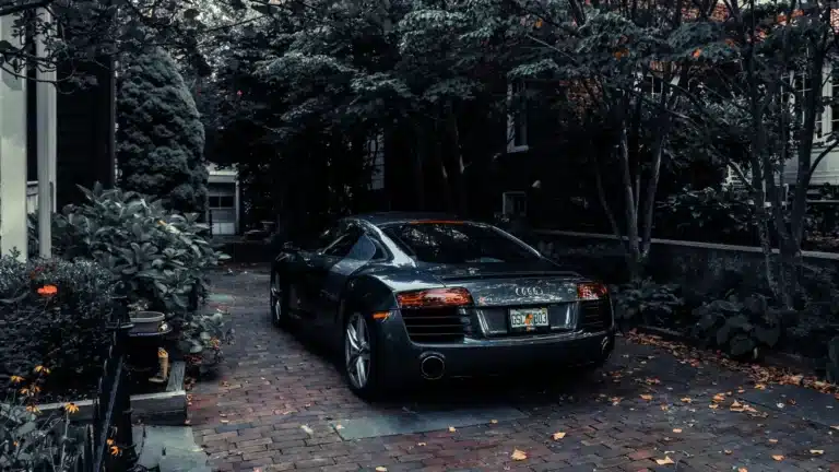 A sleek Audi R8 parked in a leafy residential driveway in Cape May, NJ, showcasing elegance and luxury.