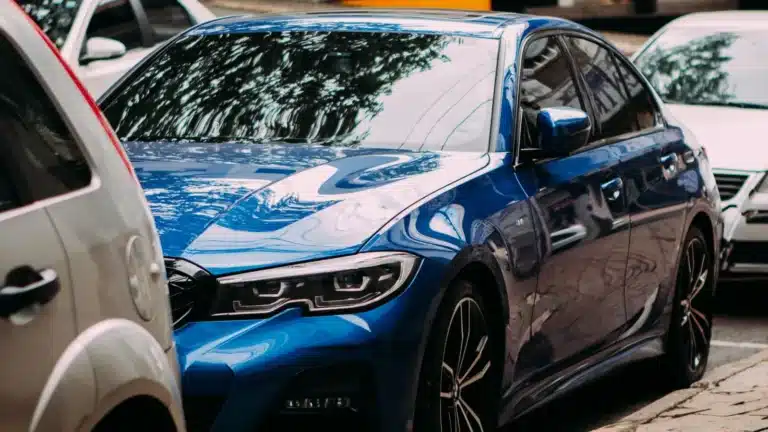 A vibrant blue luxury sedan parked on an urban street among cars.