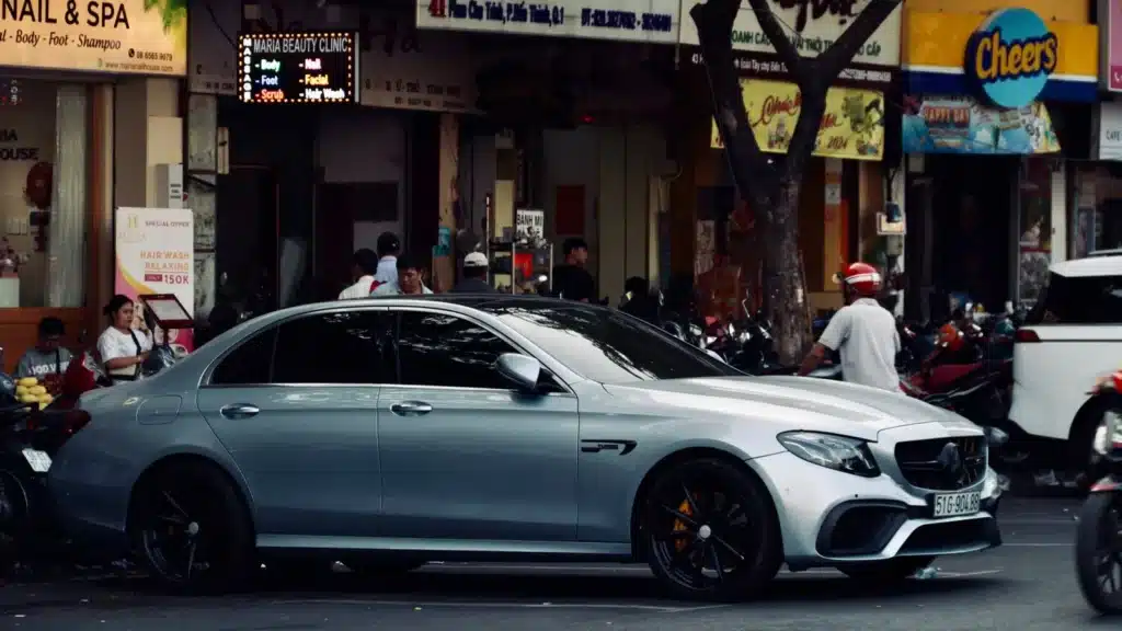 A high-end silver car parked on a bustling urban street, capturing city life.