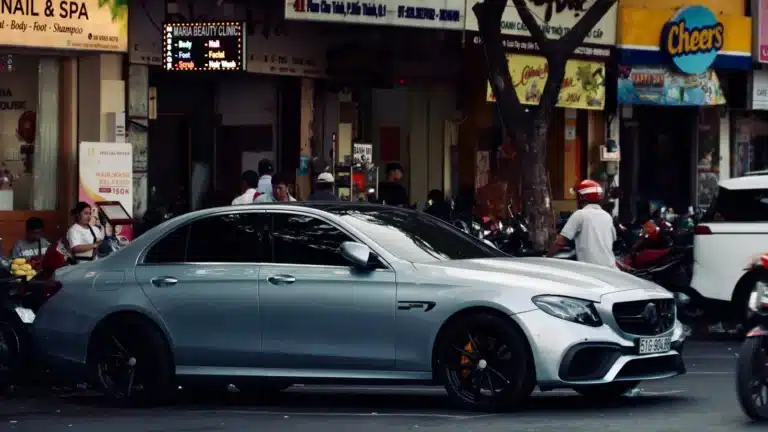 A high-end silver car parked on a bustling urban street, capturing city life.