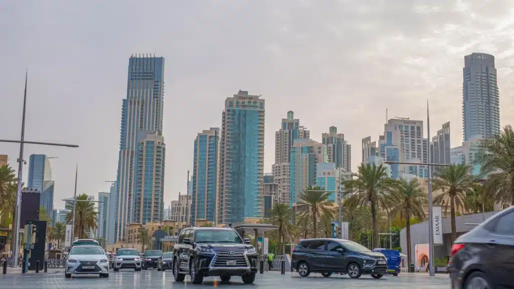 Dubai's towering skyscrapers against a bustling road, highlighting urban life.