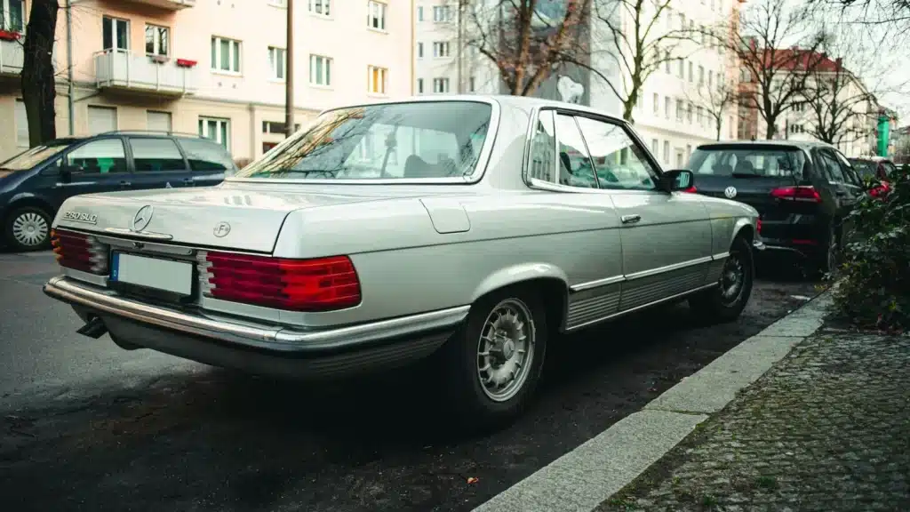 Vintage Mercedes-Benz 280 SLC automobile parked in a city street setting, showcasing classic elegance.