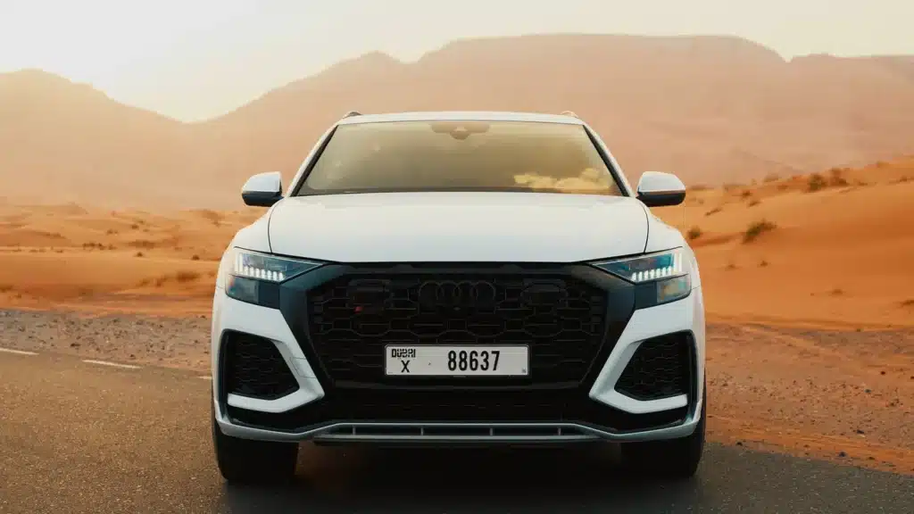 Luxury SUV on a desert road at sunset with scenic sand dunes in the background.
