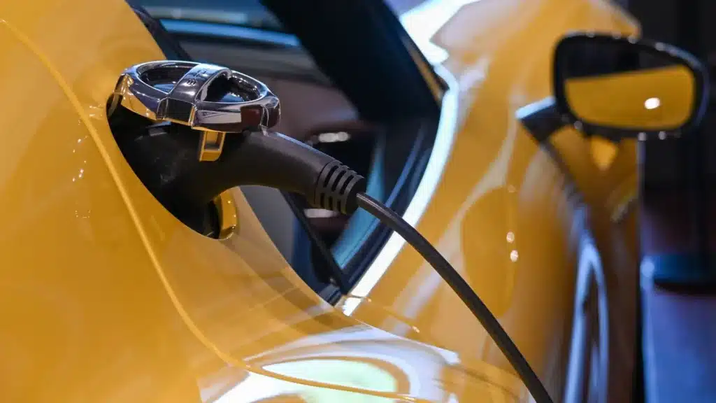 Close-up of a yellow electric vehicle charging indoors.