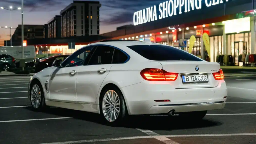 A luxury white car parked in an urban setting at twilight.